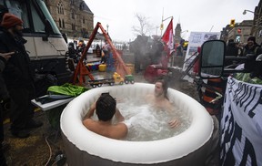 Protesters go for a soak in an inflatable hot tub along Wellington Street across from West Block on Parliament Hill on the 21st day of a protest against COVID-19 measures that has grown into a broader anti-government protest, in Ottawa, on Thursday, Feb. 17, 2022. THE CANADIAN PRESS/Justin Tang