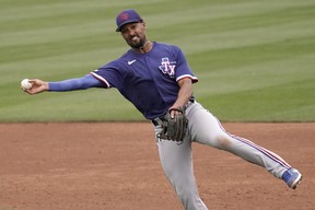 Texas Rangers shortstop Marcus Semien throws to first too late to get the out on a single hit by Seattle Mariners’ J.P. Crawford during the third inning of a spring training baseball game Monday, March 28, 2022, in Peoria, Ariz.