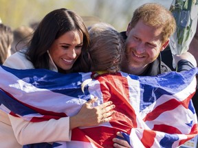 Prince Harry and Meghan Markle, Duke and Duchess of Sussex, hug Lisa Johnston, a former army medic and amputee, who celebrates with her medal at the Invictus Games venue in The Hague, Netherlands, Sunday, April 17, 2022.