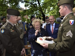 Soldiers from U.S. Army Garrison Italy return a birthday cake to Meri Mion, centre, in Vicenza, northern Italy, Thursday, April 28, 2022, to replace the one U.S. soldiers ate as they entered her hometown during one of the final battles of the Second World War.