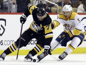 Penguins centre Evgeni Malkin (left) handles the puck against Predators defenceman Matt Benning (right) during third period NHL action at PPG Paints Arena in Pittsburgh, Sunday, April 10, 2022.