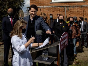 Prime Minister Justin Trudeau adjusts the microphone for Finance Minister and Deputy PM Chrystia Freeland as they highlight his government's new budget with a visit to Hamilton, Ont., Friday, April 8, 2022.