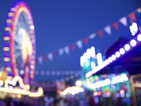 A defocused carnival scene with a ferris wheel in the backround.