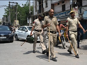 Police walk along a street in Jahangirpuri area in New Delhi on April 17, 2022, after clashes broke out between members of two communities on April 16 during a Hanuman Jayanti religious procession.