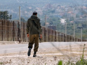 An Israeli soldier patrols along the road by the security fence near Ibthan in central Israel separating it from the occupied West Bank on April 13, 2022.