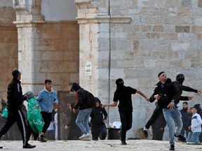 Palestinian demonstrators hurl rocks during clashes with Israeli security forces inside Jerusalem's Al-Aqsa Mosque complex, Friday, April 22, 2022.