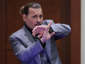 Actor Johnny Depp demonstrates how he said he defended himself from an alleged attack from his ex-wife Amber Heard as he testifies during a libel trial against Heard in Fairfax County District Court in Fairfax, Virginia. on Wednesday, April 20, 2022.