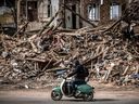 Ein Mann fährt am 2. April 2022 mit einem Roller an den Trümmern eines zerstörten Gebäudes in der ostukrainischen Stadt Charkiw vorbei, wie die Ukraine heute mitteilte, dass russische Streitkräfte einen Angriff machten 