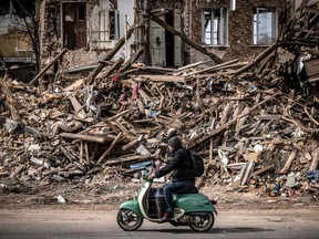 A man rides a scooter past the rubble of a destroyed building in the eastern Ukraine city of Kharkiv on April 2, 2022, as Ukraine said today Russian forces were making a