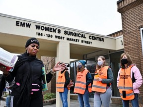 An anti-abortion protester recites scripture from the Bible while clinic escorts stand nearby at the EMW Women's Surgical Center, days after the Kentucky state legislature enacted a sweeping anti-abortion law in Louisville, April 16, 2022.