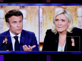 A picture shows TV screens displaying a live televised between French President and La Republique en Marche (LREM) party candidate for re-election Emmanuel Macron and French far-right party Rassemblement National presidential candidate Marine Le Pen, broadcasted on French TV channels TF1 and France 2,  in Saint-Denis, north of Paris, ahead of the second round of France's presidential election.