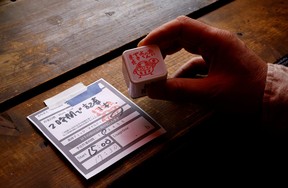 Takuya Kawai, the owner of the Manuscript Writing Cafe which is designed for writers who are working on a deadline, shows a slip of paper on which customers write down goals and the amount of time they plan to finish it in along with a stamp that clears the goal of a customer at the cafe in Tokyo, Japan, April 21, 2022.