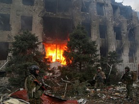 Service members of pro-Russian troops, including fighters of the Chechen special forces unit, stand in front of the destroyed administration building of Azovstal Iron and Steel Works in Mariupol, Ukraine April 21, 2022.