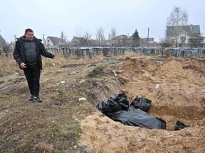 A man gestures at a mass grave in the town of Bucha, northwest of the Ukrainian capital Kyiv on April 3, 2022.