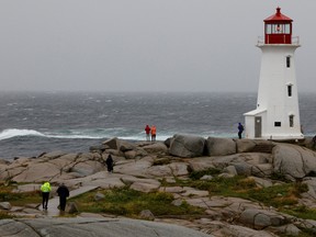 Two RCMP officers walk towards the Peggy's Cove Lighthouse to warn individuals of the dangers during the arrival of Hurricane Dorian September 7, 2019.