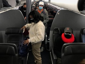 Travelers wearing masks prepare to get off an American Airlines flight at Ronald Reagan Washington National Airport in Washington, D.C., December 18, 2021.