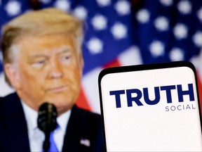 The Truth Social network logo is seen on a smartphone in front of a display of former U.S. President Donald Trump in this picture illustration taken Feb. 21, 2022.