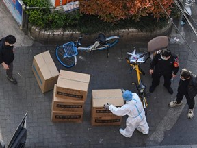 A worker wearing personal protective equipment unloads boxes during a COVID-19 lockdown in Shanghai's Jing'an district on Thursday, April 7, 2022.