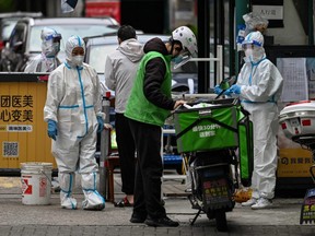 Workers are seen at the entrance of a neigbourhood during a COVID-19 lockdown in the Jing'an district in Shanghai, China, Saturday, April 30, 2022.