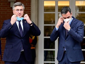 Spanish Prime Minister Pedro Sanchez (right) and his Croatian counterpart, Andrej Plenkovic, remove their face masks as they pose for photographers prior to holding a meeting at La Moncloa palace in Madrid, March 16, 2022.