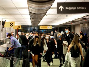 Travellers wearing protective face masks to prevent the spread of COVID-19 reclaim their luggage at the airport in Denver, Col., Nov. 24, 2020.