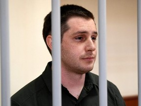 In this file photo taken March 11, 2020, U.S. ex-marine Trevor Reed, charged with attacking police, stands inside a defendants' cage during a court hearing in Moscow.