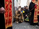 Menschen knien während der Trauerfeier für Yuriy Dadak-Ruf und Taras Kryt, die durch Artilleriebeschuss in der Region Luhansk in Lemberg, Ukraine, am 9. April 2022 getötet wurden