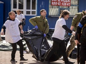 Ukrainian soldiers clear out bodies in bags after a rocket attack killed dozens of people at a train station in Kramatorsk, Ukraine, Friday, April 8, 2022.