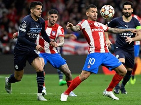 Atletico Madrid's Argentinian forward Angel Correa controls the ball while being challenged by Manchester City's Portuguese defender Joao Cancelo (L) during the UEFA Champions League quarter final second leg football match between Club Atletico de Madrid and Manchester City FC at the Wanda Metropolitano stadium in Madrid on April 13, 2022.