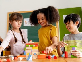 Children play with wooden blocks in a classroom.