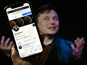 In this photo illustration, a phone screen displays the Twitter account of Elon Musk with a photo of him shown in the background, on April 14, 2022, in Washington, DC.