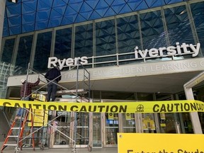 Crews are pictured as they take down a "Ryerson University" sign off one of the institution's buildings. The school will now be called Tornto Metropolitan University.