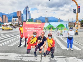 The author posing with Ciclovia support staff at a red light stop. The sign encourages all rideres to wear helmets for safety.