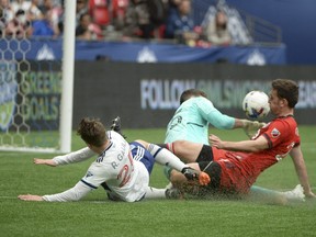 Toronto FC goalkeeper Alex Bono (25) and defender Shane O'Neill (27) defend against Vancouver Whitecaps midfielder Ryan Gauld.