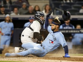 Lourdes Gurriel Jr. #13 of the Toronto Blue Jays scores past Jose Trevino #39 of the New York Yankees in the eighth inning on a sacrifice fly at Yankee Stadium on May 10, 2022 in New York City.