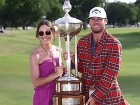 Sam Burns of the United States poses with the Leonard Trophy and wearing the Colonial Country Club plaid jacket with his wife Caroline after putting in to win on the 18th green during the first playoff hole during the final round of the Charles Schwab Challenge at Colonial Country Club on May 29, 2022 in Fort Worth, Texas. (Photo by Tom Pennington/Getty Images)
