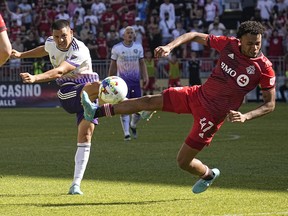 Orlando City SC midfielder Cesar Araujo kicks the ball as Toronto FC midfielder Kosi Thompson defends.