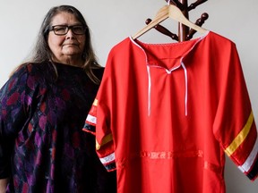 Joanne Anderson, who is Métis and chair of Union Gospel Mission's anti-racism committee, with a red dress made by her aunt, Agnes Sinclair, a Cree matriarch and a seamstress. The dress will be hung in UGM's Women and Families Centre to help Indigenous women in their healing journeys. Photo credit: Solomon Hsu [PNG Merlin Archive]