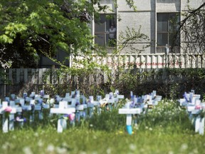 A man looks out the window at the Camilla Care Community centre overlooking crosses marking the deaths of multiple people that occured during the COVID-19 pandemic in Mississauga, Ont., on Tuesday, May 26, 2020.