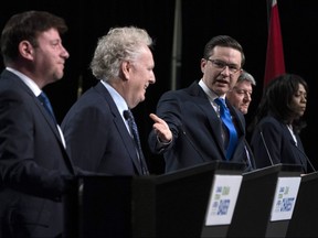 Conservative leadership candidate Pierre Poilievre gestures towards Jean Charest as Roman Baber, left, Scott Aitchison and Leslyn Lewis, right, debate at the Canada Strong and Free Network conference, in Ottawa, Thursday, May 5, 2022.