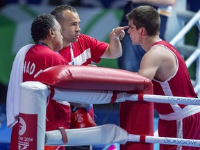 Canada's Brody Blair from New Glasgow, N.S. talks with coaches Daniel Trepanier and Kevin Howard, left, after fighting Abdul Bangura of Sierra Leone in 75 kg boxing action at the Commonwealth Games in Glasgow, Scotland on Saturday, July 26, 2014.
