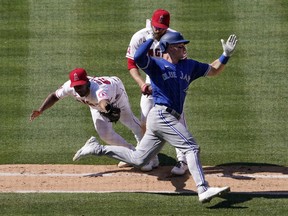 Toronto Blue Jays' Matt Chapman avoids a tag by  Angels relief pitcher Oliver Ortega, left, on his way to an infield single as first baseman Jared Walsh looks on during the seventh inning Sunday, May 29, 2022, in Anaheim, Calif.