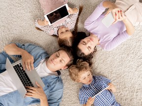 Top view of young family lying on the floor and scrolling in mobile gadgets