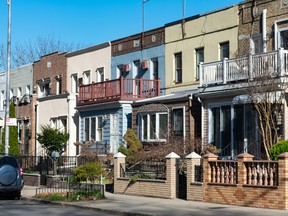 A row of beautiful and colorful old brick homes along the sidewalk in Queens, New York