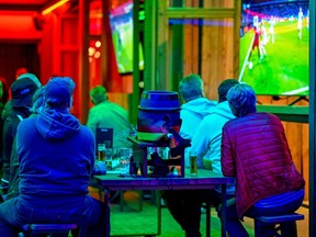 People sit as they watch the UEFA EURO 2020 Group F football match between Germany and Hungary broadcasted near the Rheinenergie Stadium illuminated with the Rainbow colours in Cologne, western Germany, on June 23, 2021. (Photo by SASCHA SCHUERMANN/AFP via Getty Images)
