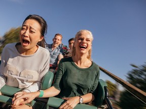 Friends cheering and riding roller coaster at amusement park