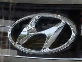 The company logo of Hyundai Motor on a Santa Fe sport utility vehicle and a woman's reflection is seen through the window of a Hyundai dealership in Seoul July 2, 2012.