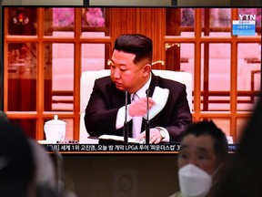 Menschen sitzen in der Nähe eines Bildschirms, der am Donnerstag, den 12. Mai 2022, eine Nachrichtensendung an einem Bahnhof in Seoul zeigt, in der Nordkoreas Führer Kim Jong Un im Fernsehen eine Gesichtsmaske entfernt, um landesweite Sperrungen anzuordnen, nachdem der Norden seine allererste COVID-Bestätigung bestätigt hatte. 19 Fälle.