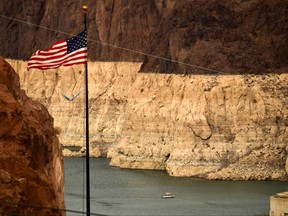 In this file photo taken on July 19, 2021, a boat sits on the water as a "bathtub ring" is visible at sunset during low water levels the Lake Mead reservoir due to the western drought s seen from the Hoover Dam, near Las Vegas.