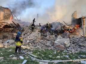 Einsatzkräfte kümmern sich um ein Feuer in der Nähe von brennenden Trümmern, nachdem ein Schulgebäude im Dorf Bilohorivka, Lugansk, Ukraine, am 8. Mai 2022 von Granaten getroffen wurde.